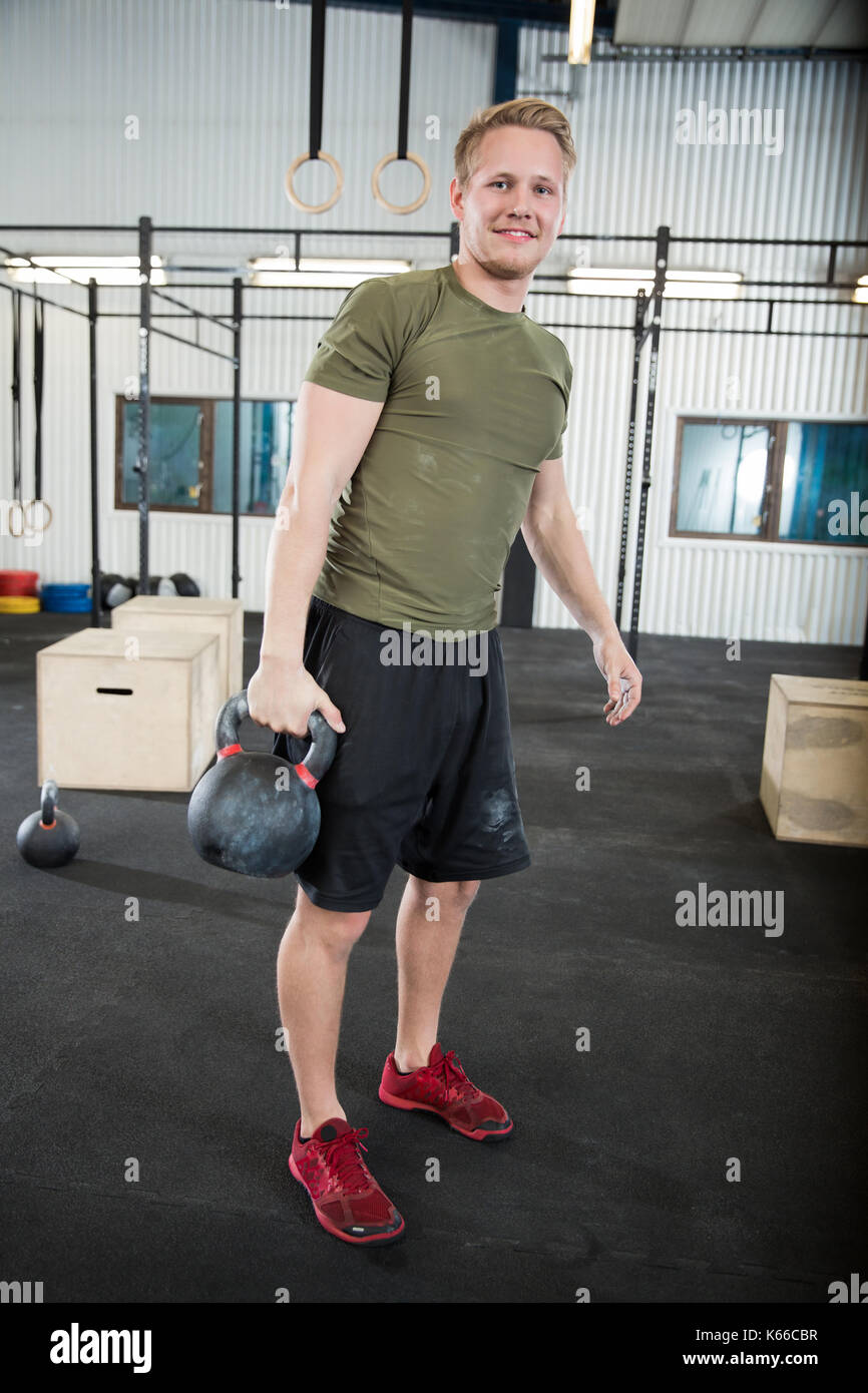 Fiducioso atleta maschio kettlebell di sollevamento nel club salute Foto Stock
