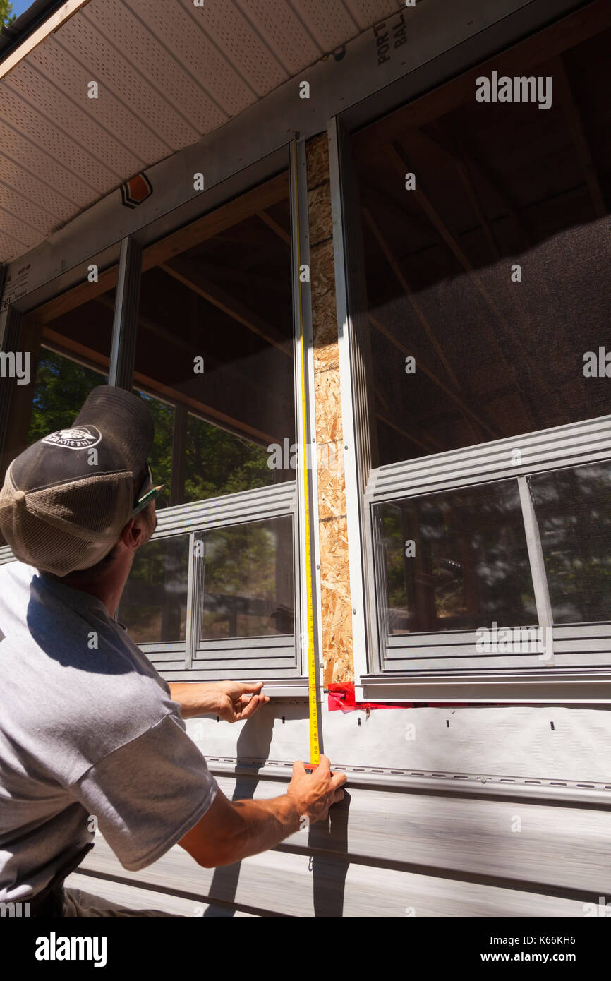 Un lavoratore edile misurando la lunghezza di una finestra utilizzando un nastro di misurazione in Ontario, Canada. Foto Stock