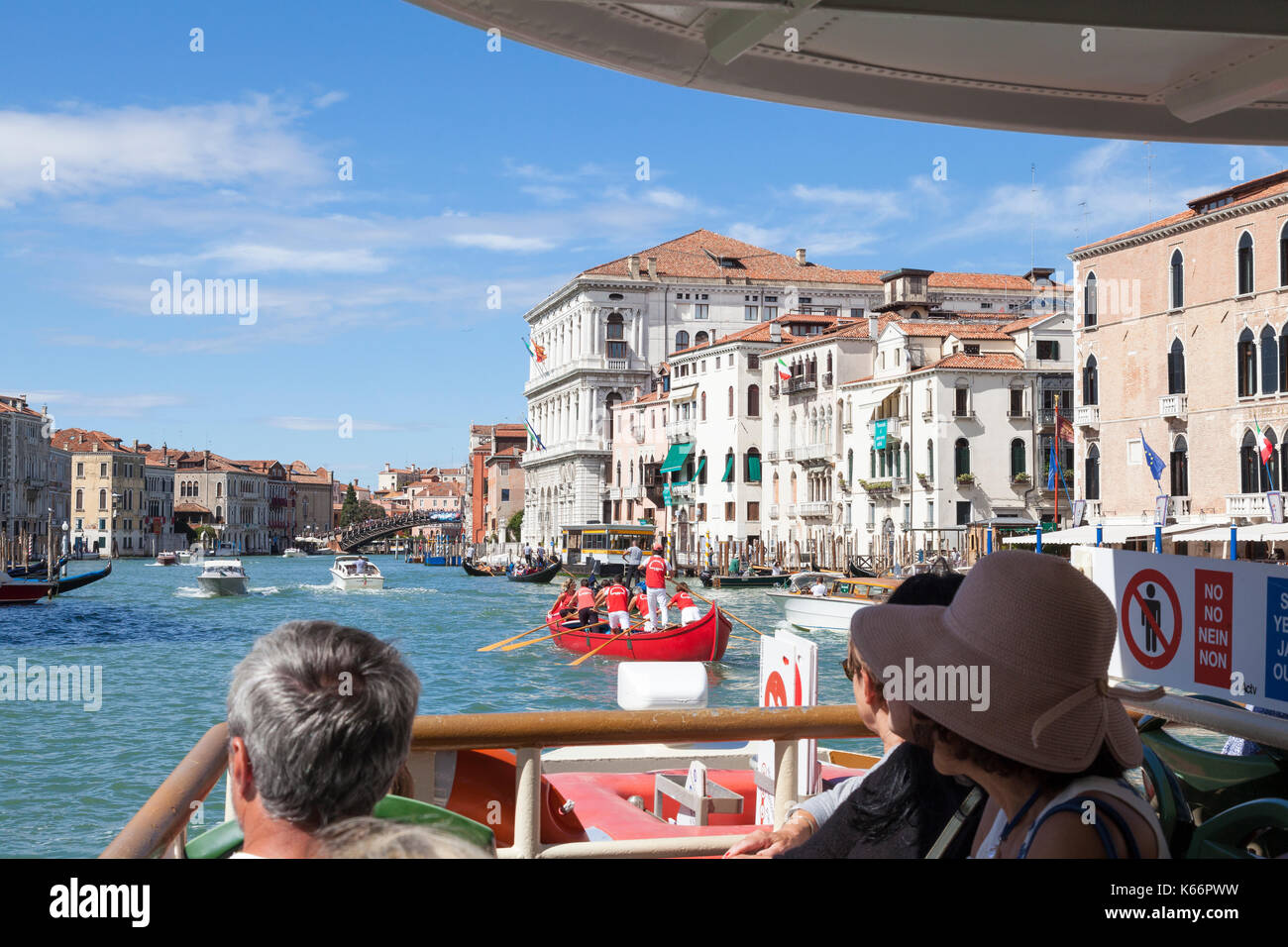 I turisti su un vaporetto che viaggiano fino al Grand Canal, Venezia, Italia da un primo punto di vista guardando oltre la prua. Team di regatanti veneziani Foto Stock