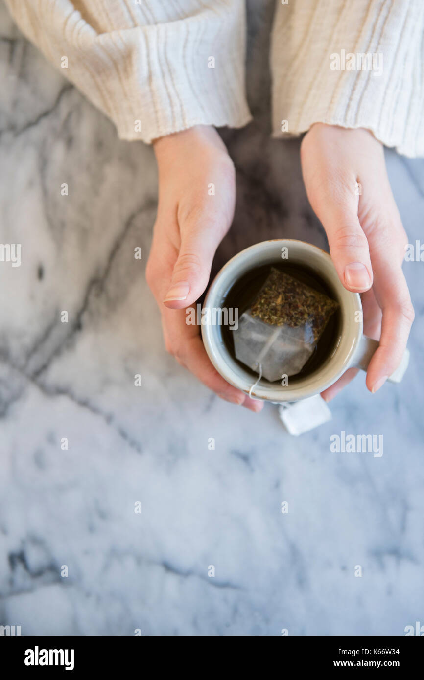 Le mani della donna caucasica holding tazza di tè Foto Stock