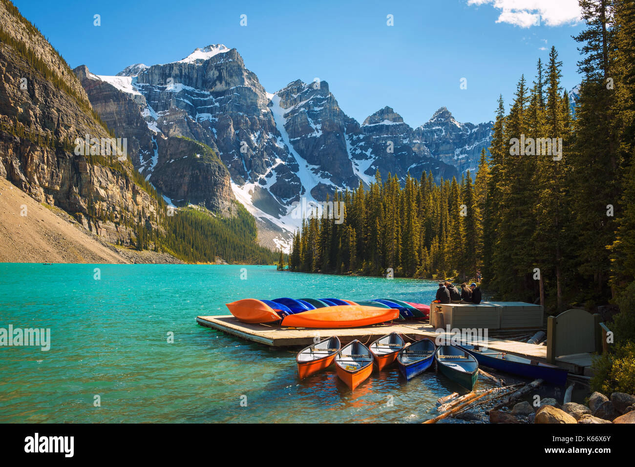 Canoe su un molo al Lago Moraine nel parco nazionale di Banff, Alberta, Canada, con cime innevate della Canadian Rocky Mountains in background. Foto Stock