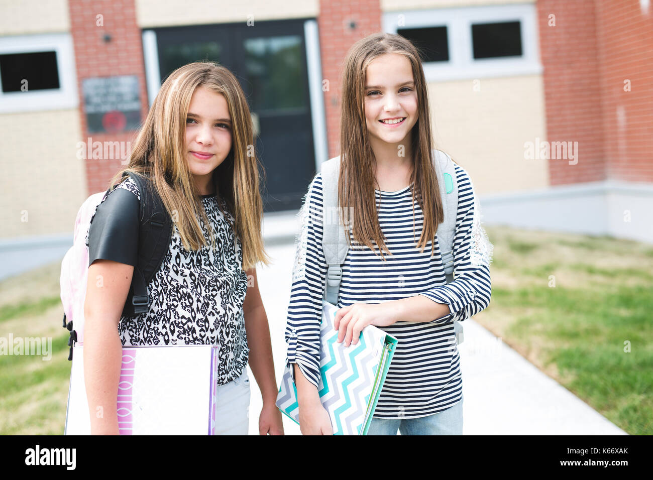 due ragazze della scuola superiore che trasportano le borse con i gesti  della mano ok Foto stock - Alamy