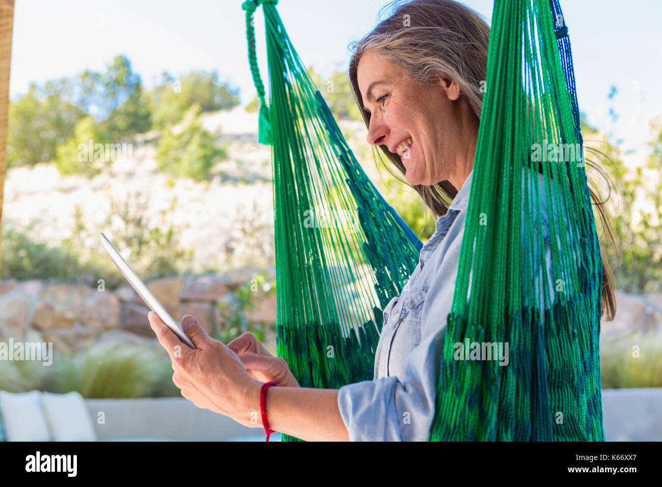I vecchi donna caucasica la lettura digitale compressa in verde amaca Foto Stock