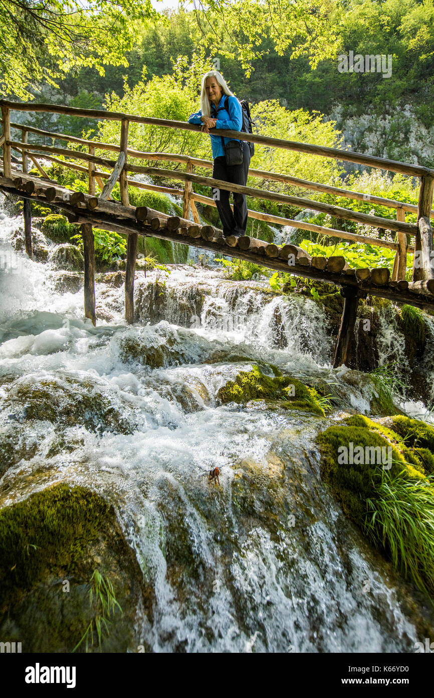 I vecchi donna caucasica sulla passerella di legno ammirando la cascata Foto Stock