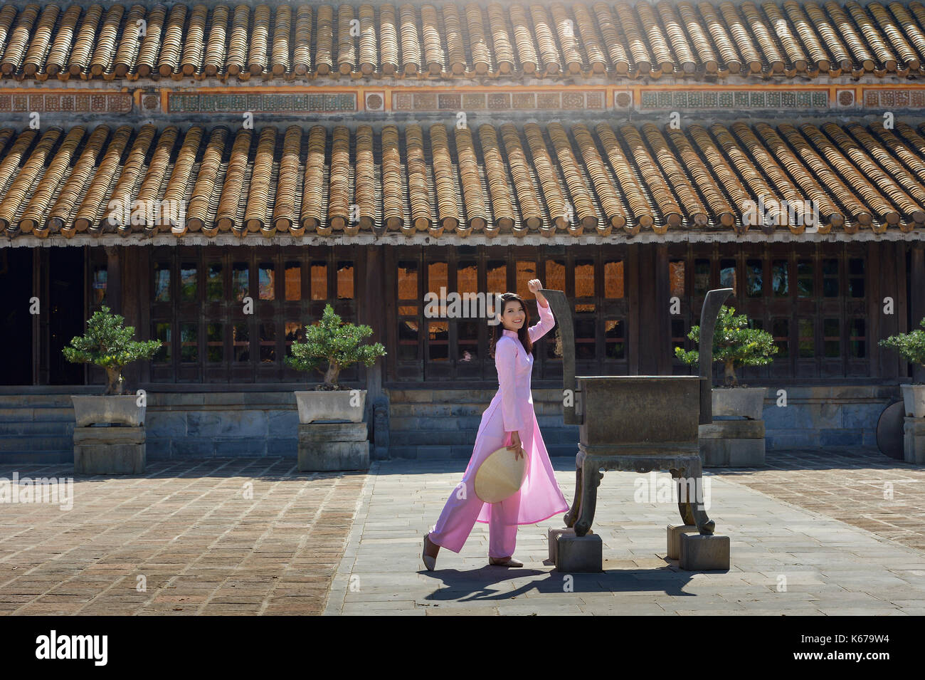 Donna camminare davanti a un edificio tradizionale, Vietnam Foto Stock