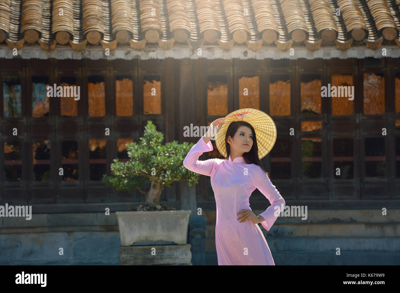 Donna in piedi da un edificio tradizionale, Vietnam Foto Stock