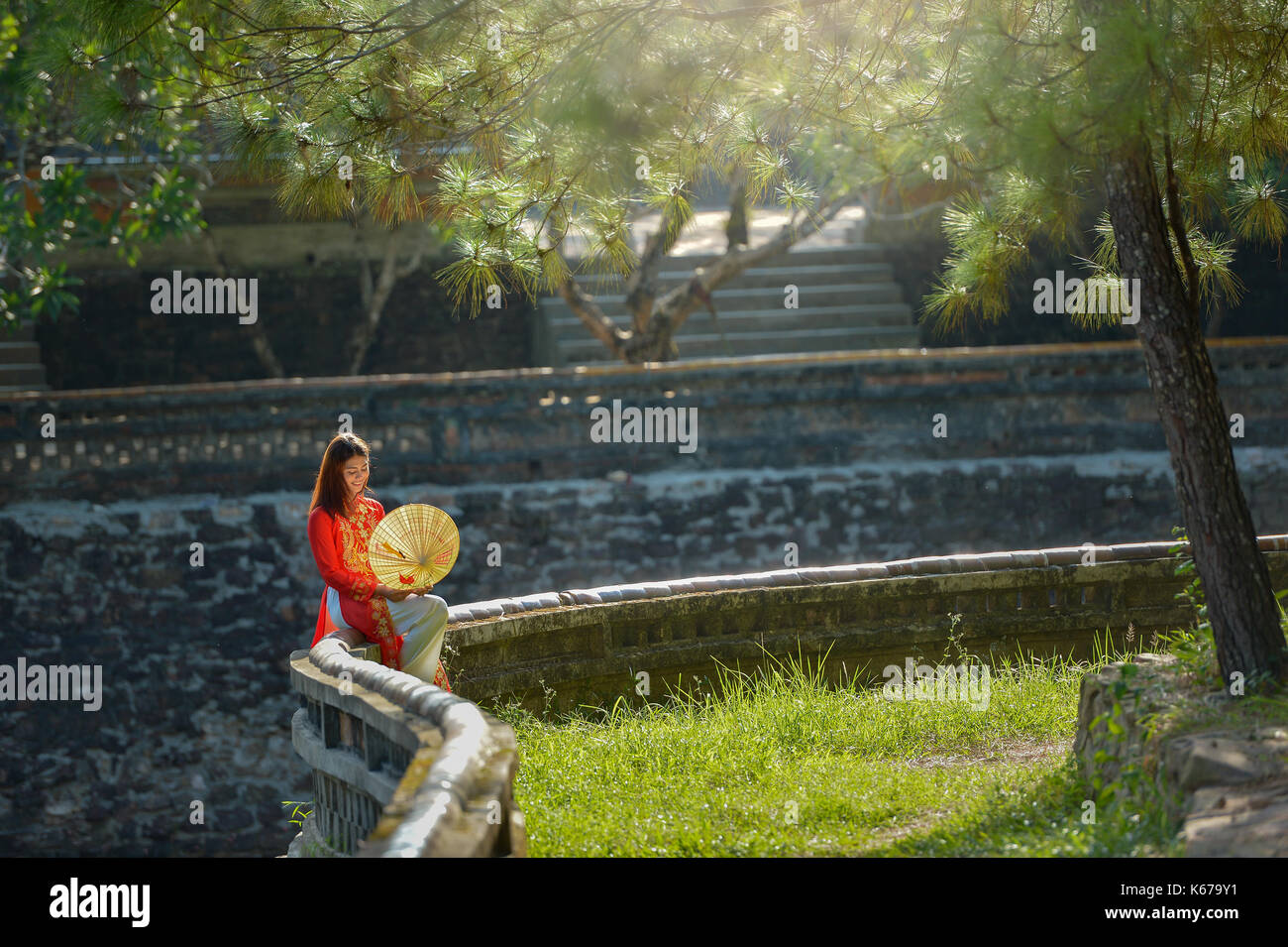 Donna in abiti tradizionali seduti su una parete, Vietnam Foto Stock