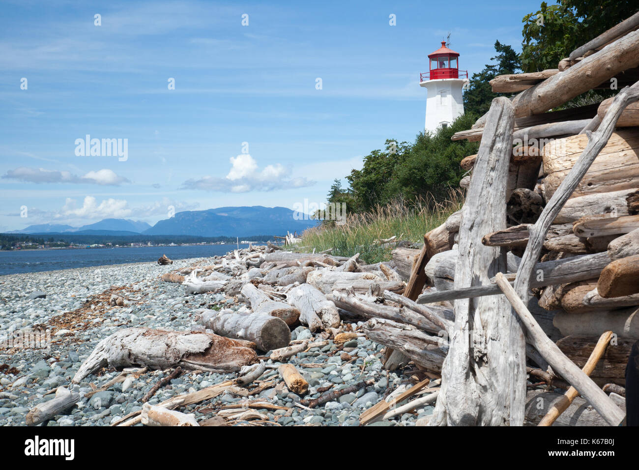 Driftwood e faro sulla spiaggia, Quadra Island, Columbia, Canada Foto Stock
