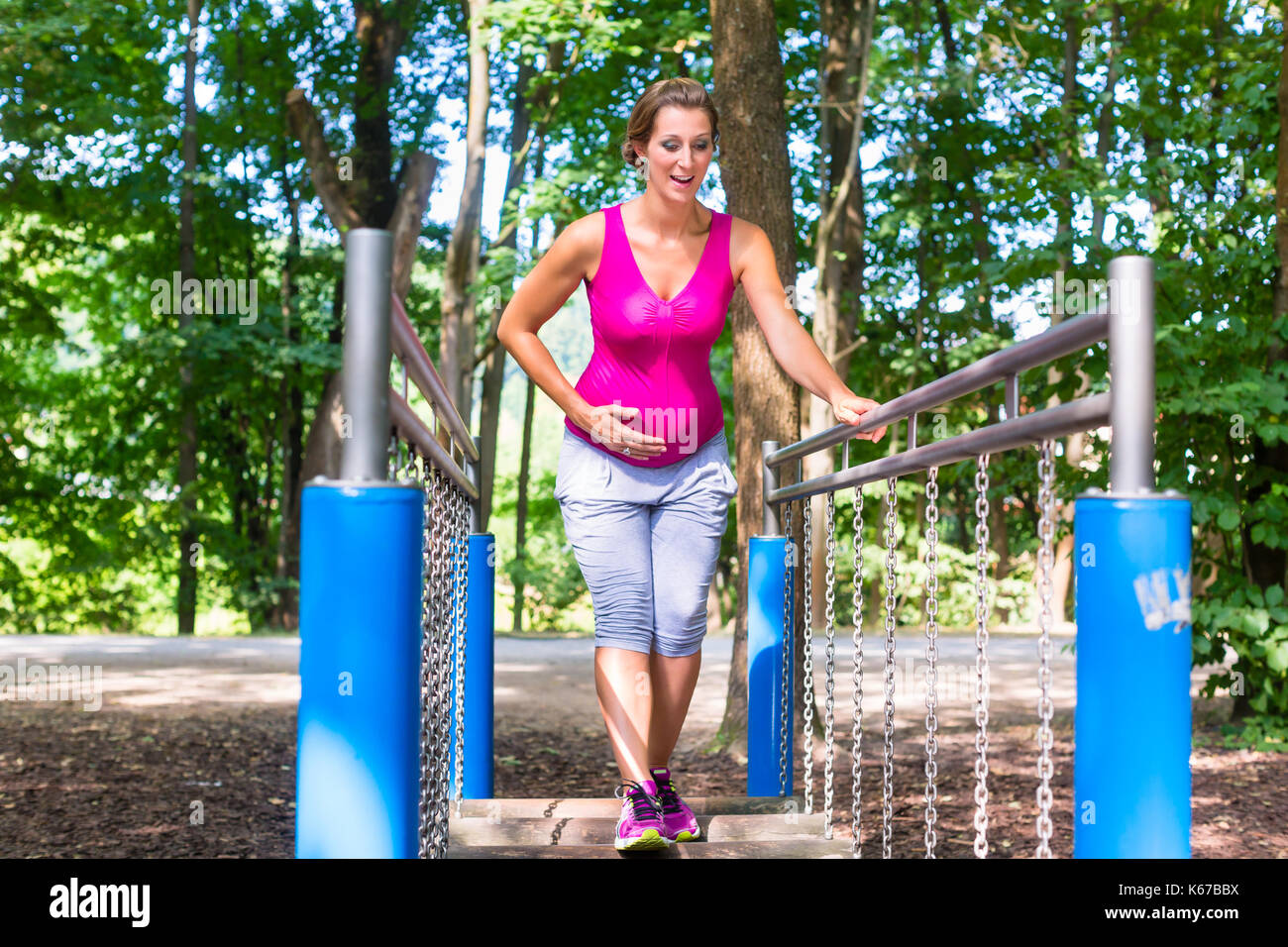 Donna incinta facendo sport fitness nel parco di arrampicata Foto Stock