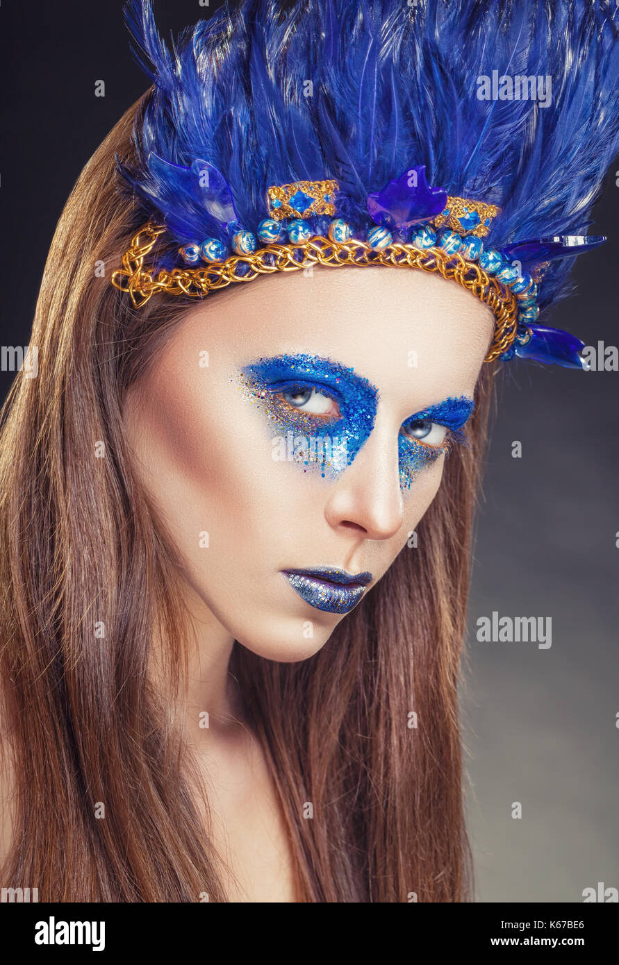 Il trucco di moda in American stile indiano. Donna attraente con il make-up con blu brillante di piume Foto Stock