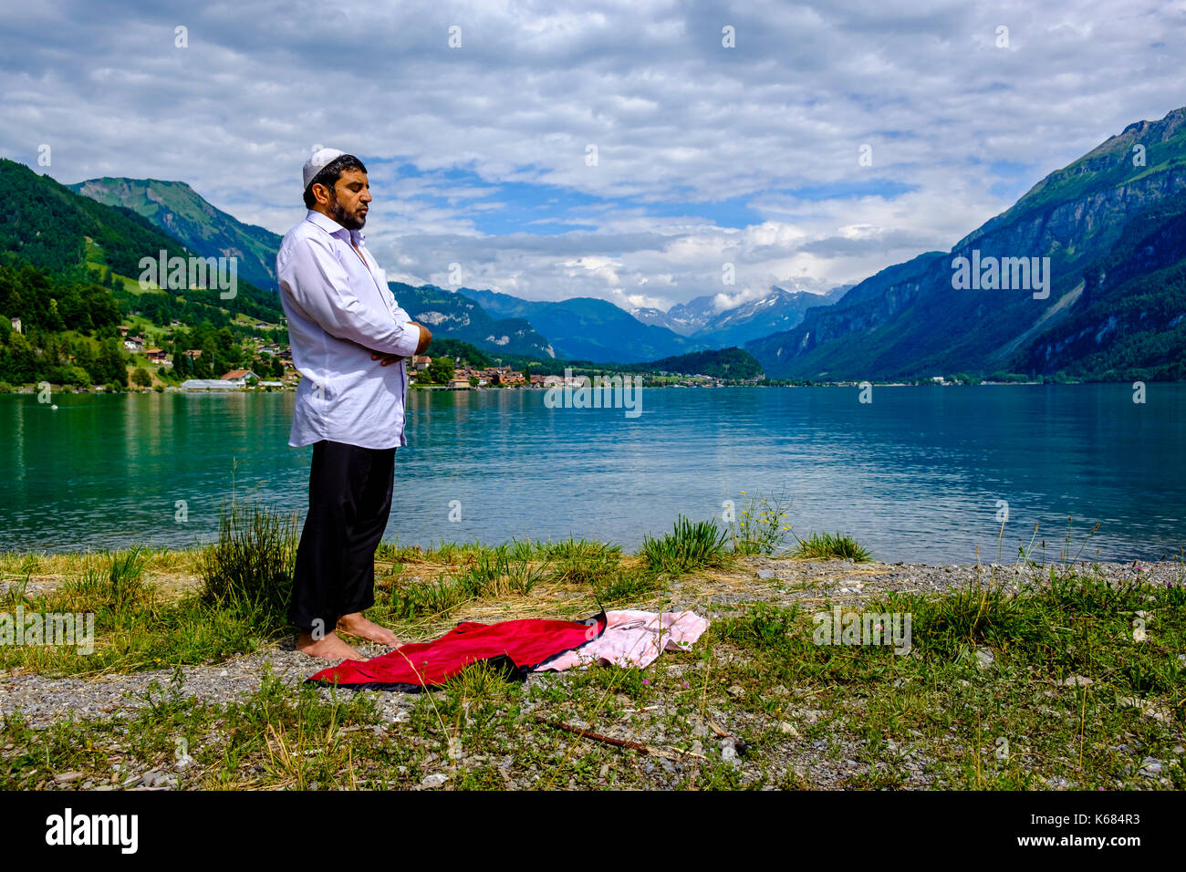 Un uomo musulmano è pregare presso il lago di Brienz, brienzer vedere, alte montagne in distanza Foto Stock