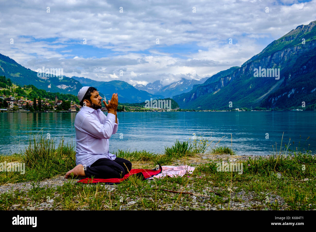 Un uomo musulmano è pregare presso il lago di Brienz, brienzer vedere, alte montagne in distanza Foto Stock