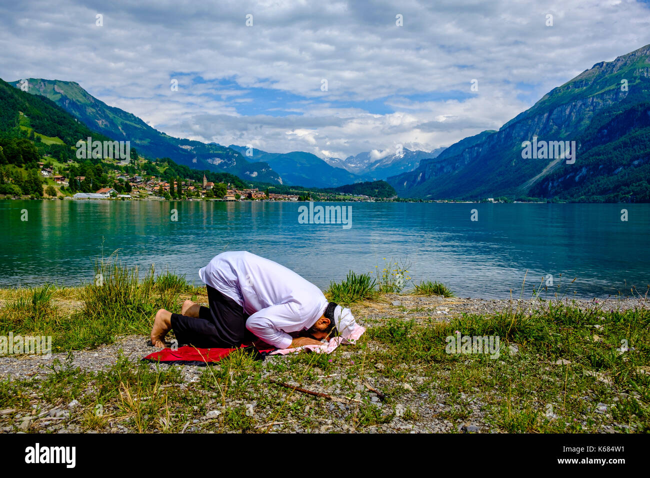 Un uomo musulmano è pregare presso il lago di Brienz, brienzer vedere, alte montagne in distanza Foto Stock