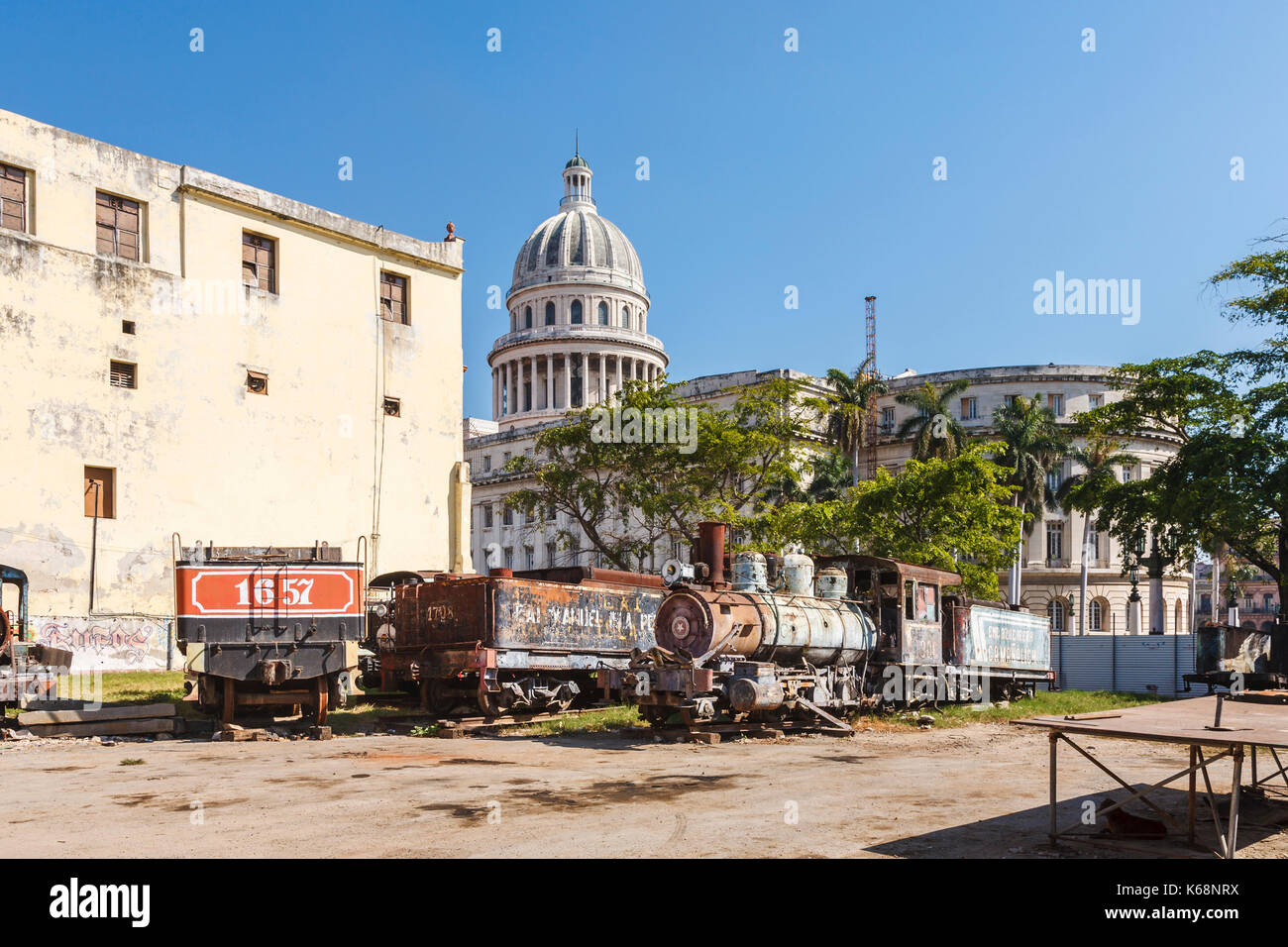Scrapyard dietro la mitica capitale nazionale edificio nel centro di Avana, capitale di Cuba, con derelitti, arrugginimento locomotore ferroviario motori Foto Stock