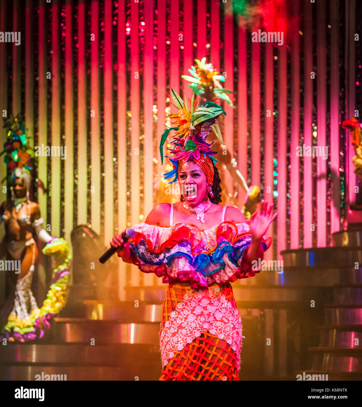 Esuberante cantante e danzatrice esotica di eseguire dal vivo sul palco in abiti colorati in uno spettacolo di cabaret per i turisti in una discoteca di Avana, Cuba Foto Stock