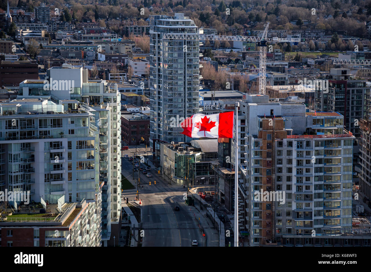 Vista aerea di una bandiera canadese sbattimenti nel vento con edifici e nuova costruzione in background. La foto è stata scattata nel centro cittadino di Vancouver, britis Foto Stock