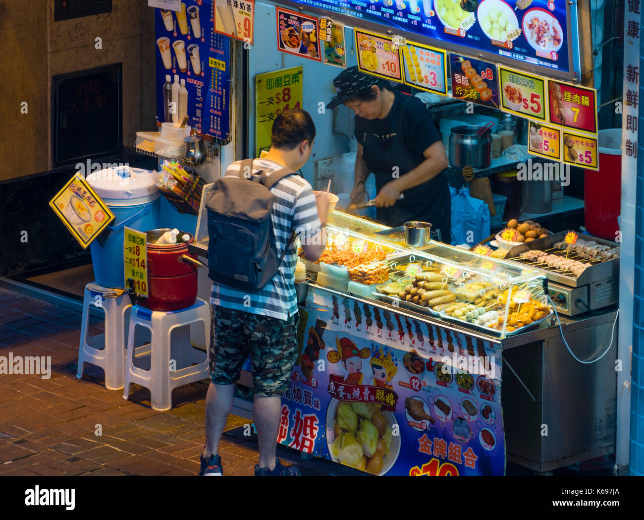 Persone che acquistano il cibo di strada in stallo alimentare di Hong kong Foto Stock