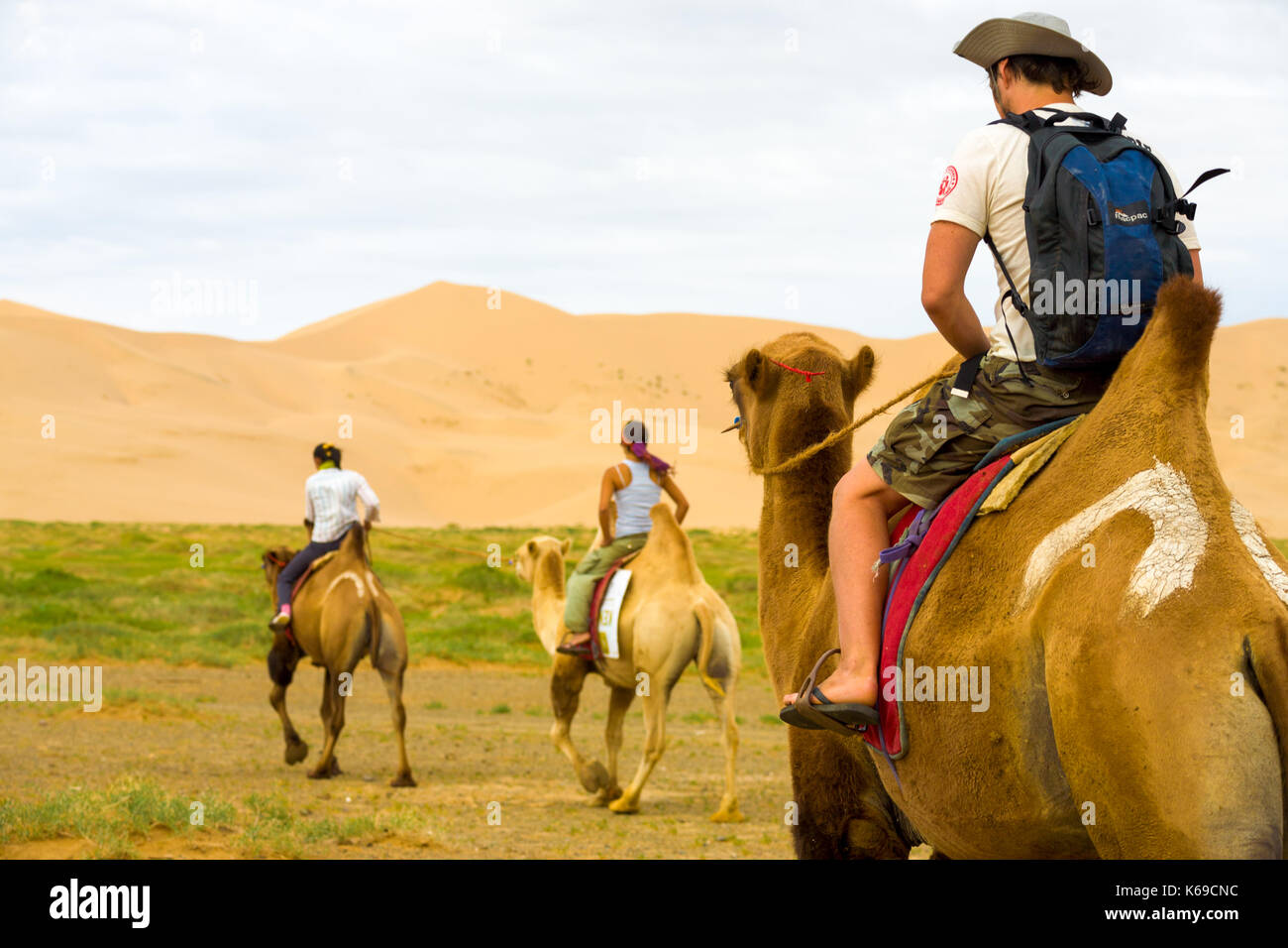 Khongor, mongolia - Luglio 20, 2007: vista posteriore di turisti stranieri in sella doppia bactrian humped cammelli al khongor dune di sabbia nel deserto del Gobi Foto Stock