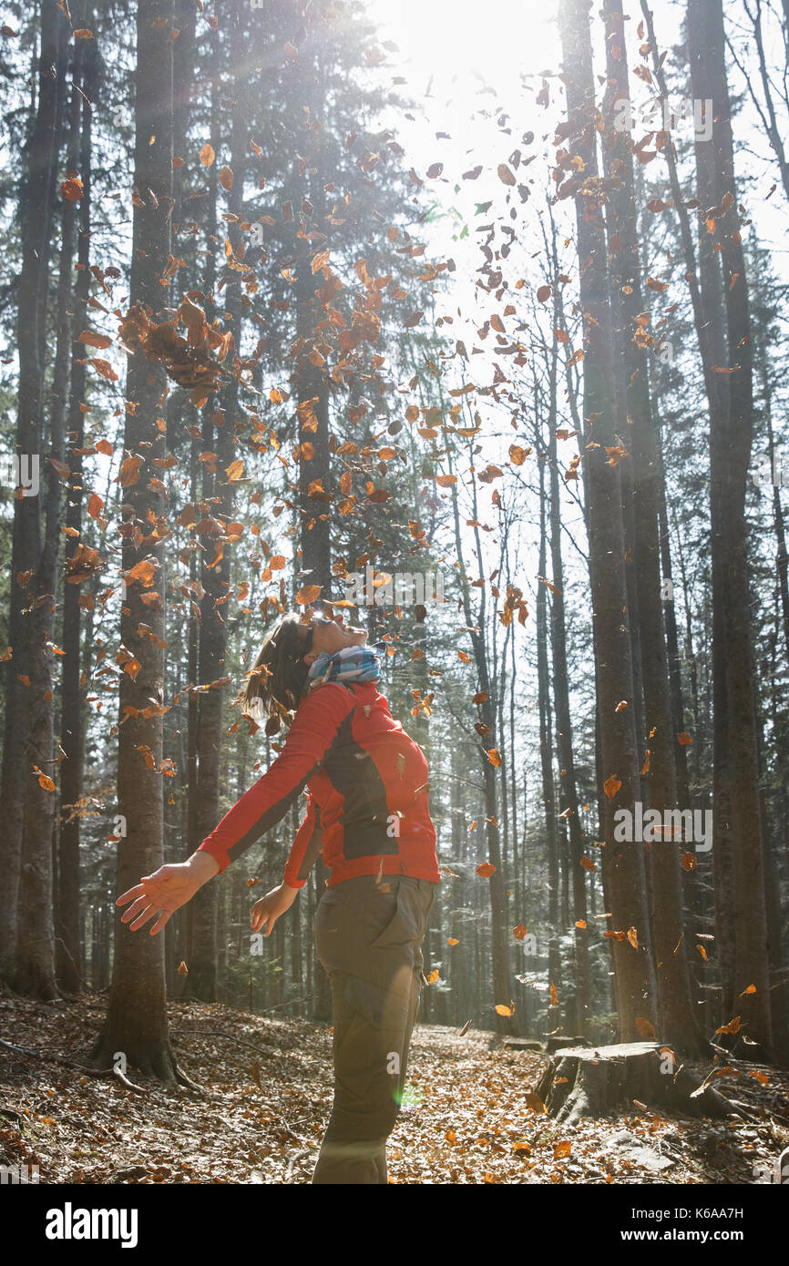 Athletic donna escursionista godendo la natura, gettando le foglie in autunno soleggiata foresta. amante della natura, uno stile di vita attivo, la felicità e il concetto di divertimento. Foto Stock