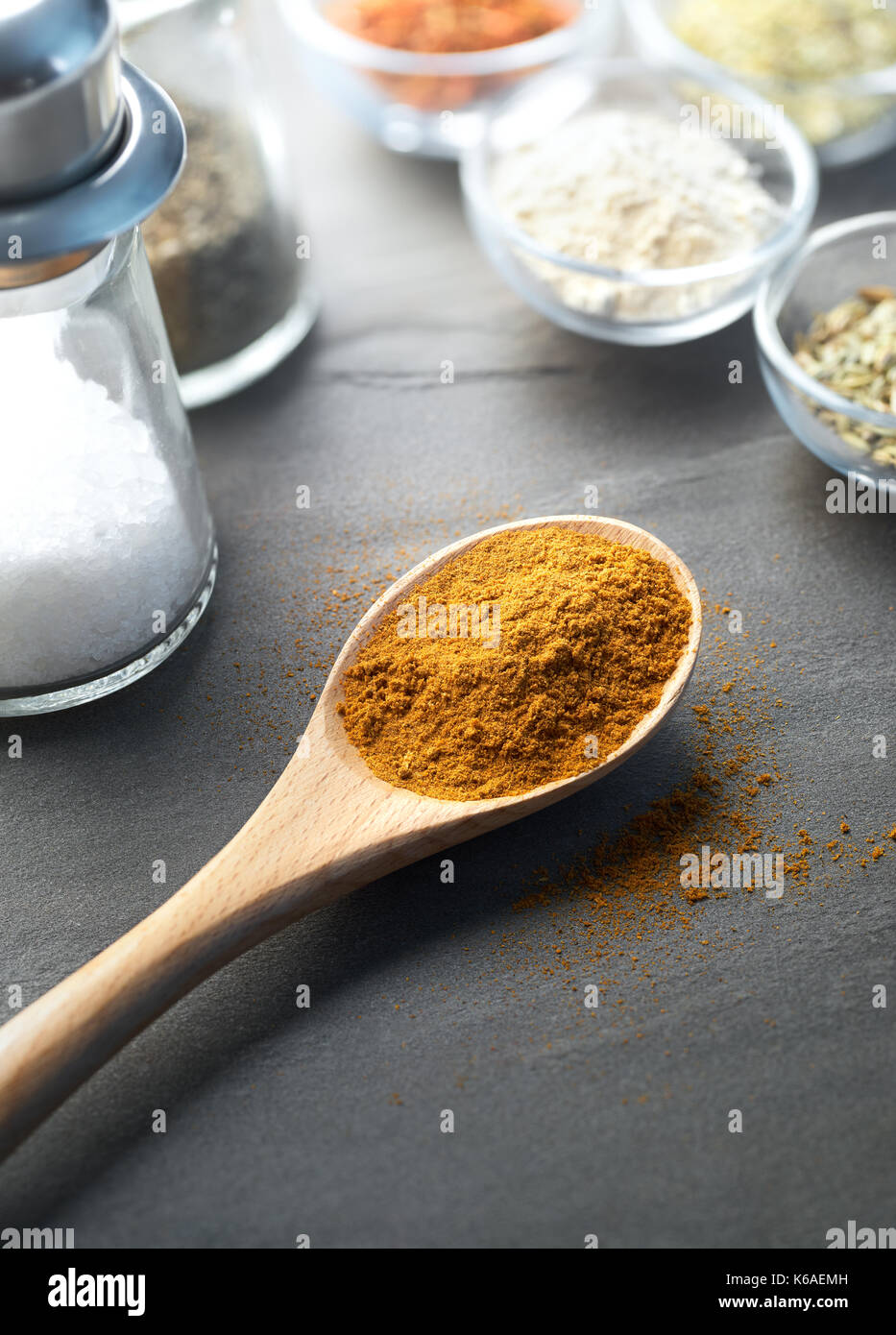 Cucchiaio di legno riempita con masala polvere e altro ingrediente Foto Stock