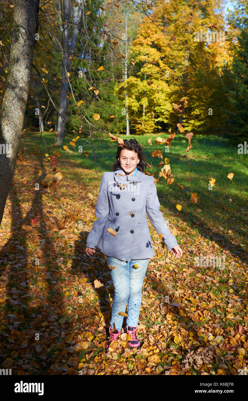 Happy young teen girl in autunno scenario gettando le foglie Foto Stock