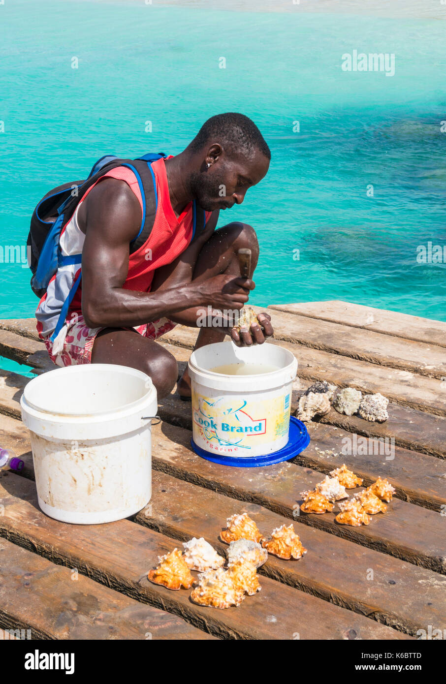 Capo Verde SAL ragazzo locale di gusci di pulizia per la vendita come souvenir sul molo in legno in Santa Maria Isola di Sal Capo verde Africa Foto Stock