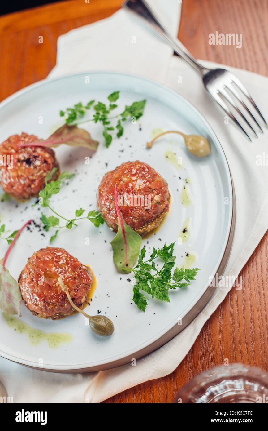 Tartara di manzo con un uovo su una lastra di pietra. pomodori ciliegia. rosmarino. spice. Foto Stock