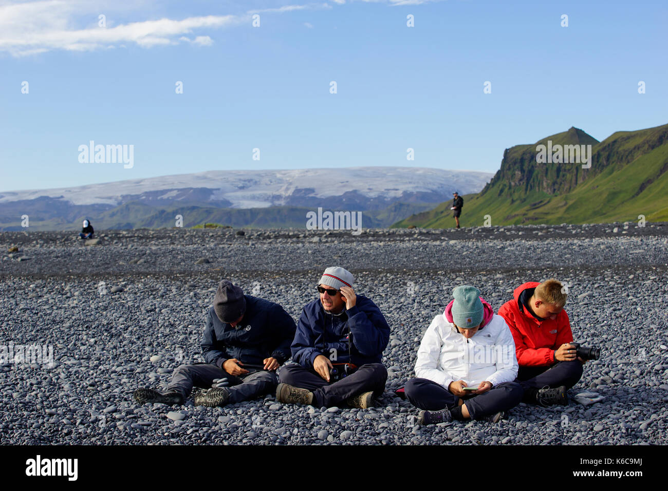 I turisti alla spiaggia di Reynisfjara, una delle attrazioni turistiche più famose in Islanda, e il cappuccio di ghiaccio che copre il vulcano Katla. Foto Stock