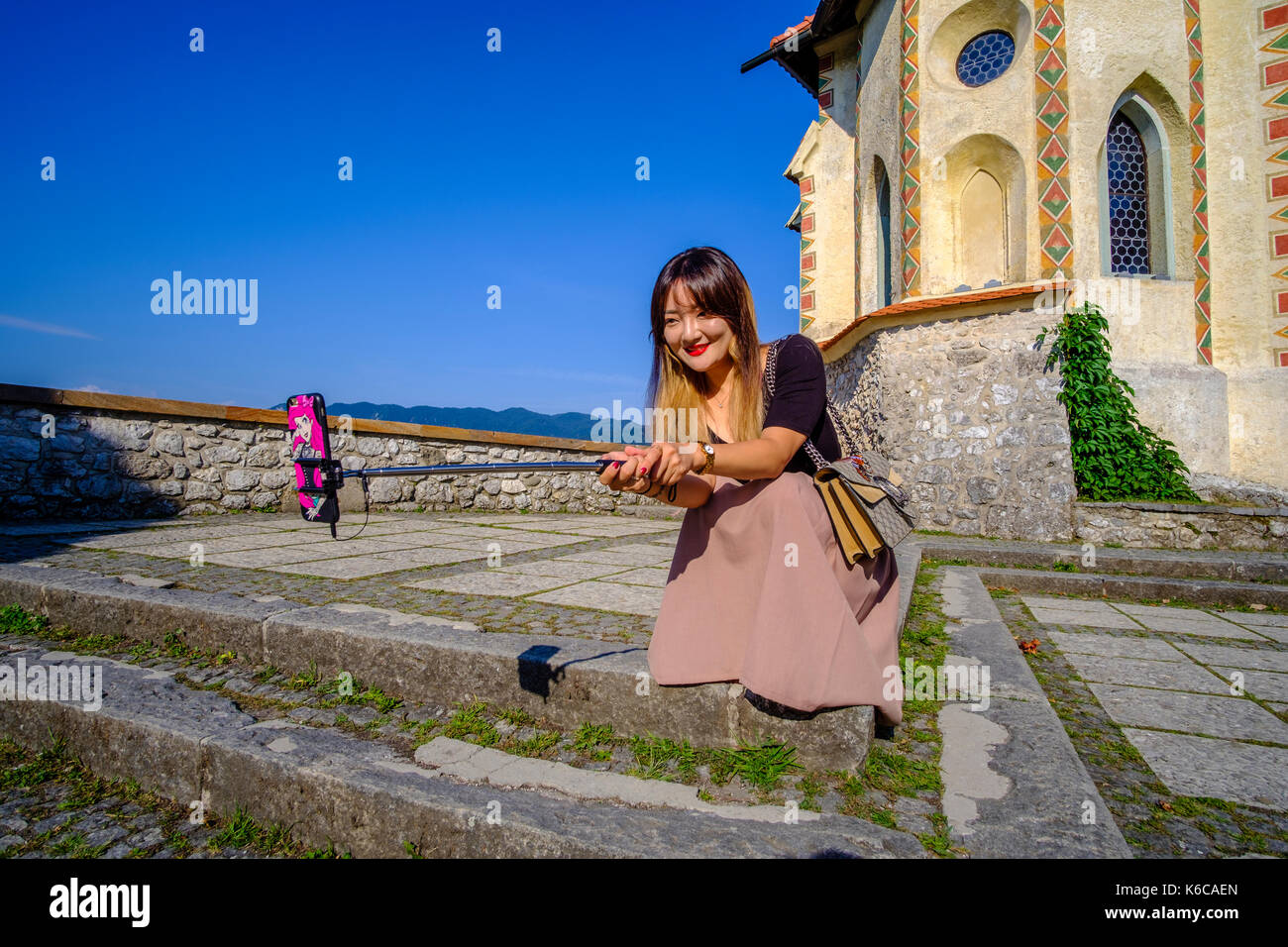 Un turista cinese donna sta prendendo un selfie all'interno del castello di Bled, blejski grad, situato su una montagna rocciosa alta al di sopra del lago di Bled, blejsko jezero Foto Stock