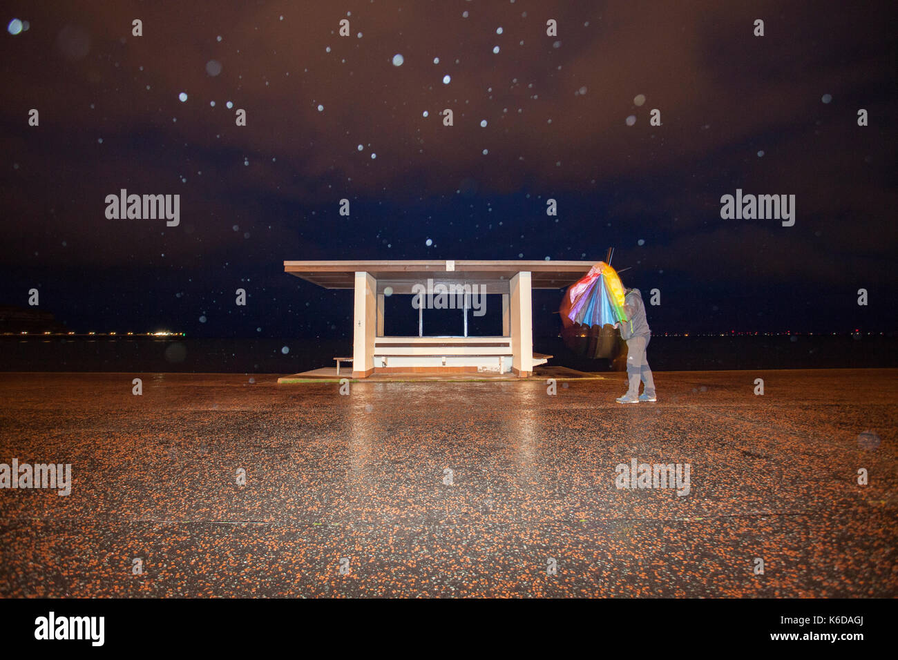 Tempesta aileen colpisce parti del regno unito con una spia di avvertimento color ambra dal Met Office per il Galles del nord. Una passeggiata rifugio a Llandudno di notte con pioggia con la persona che tiene crollato ombrello contro il vento tempestoso Foto Stock