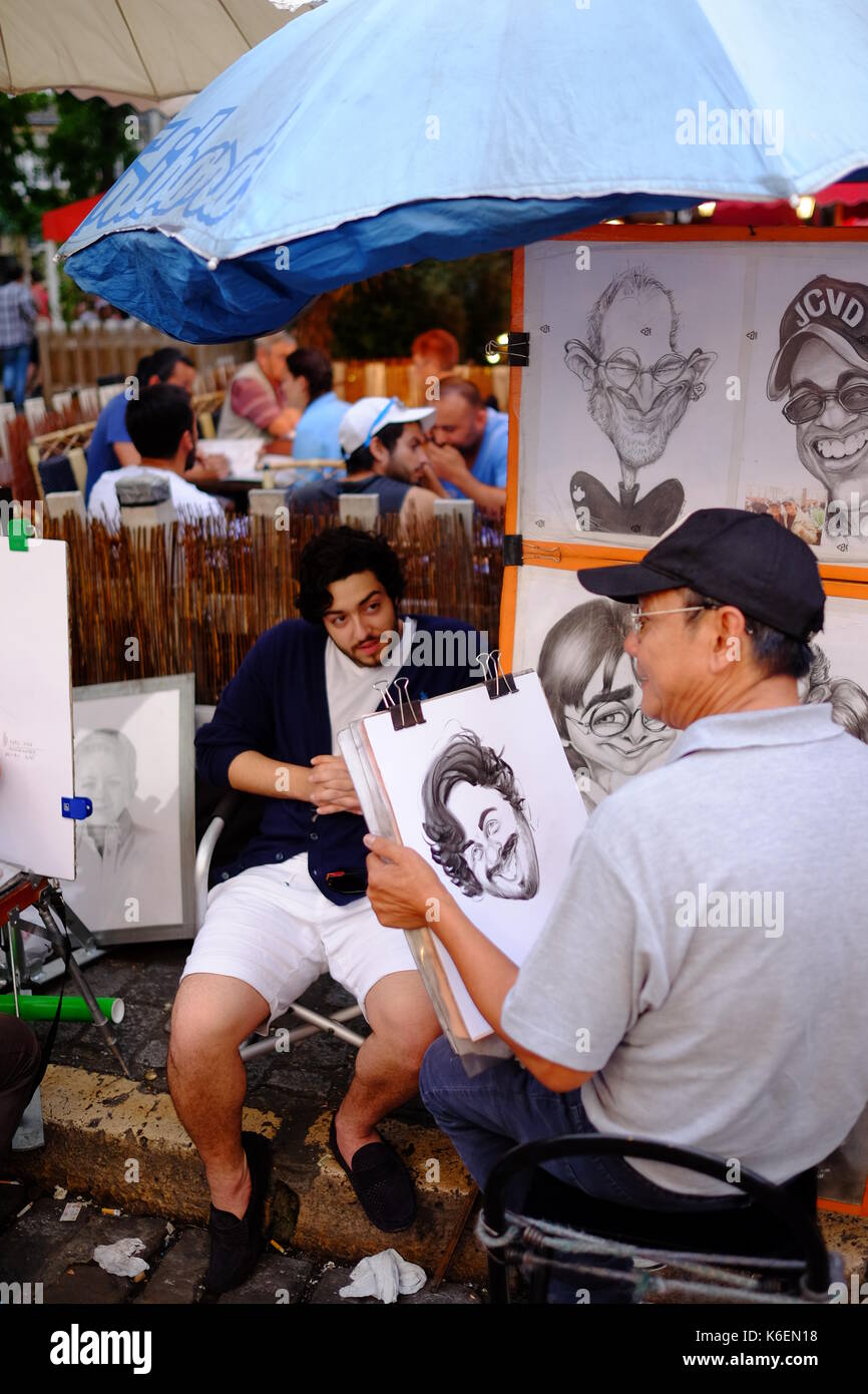 Un artista di strada completa una caricatura di un turista in Place du Tertre a Montmartre, Parigi Foto Stock