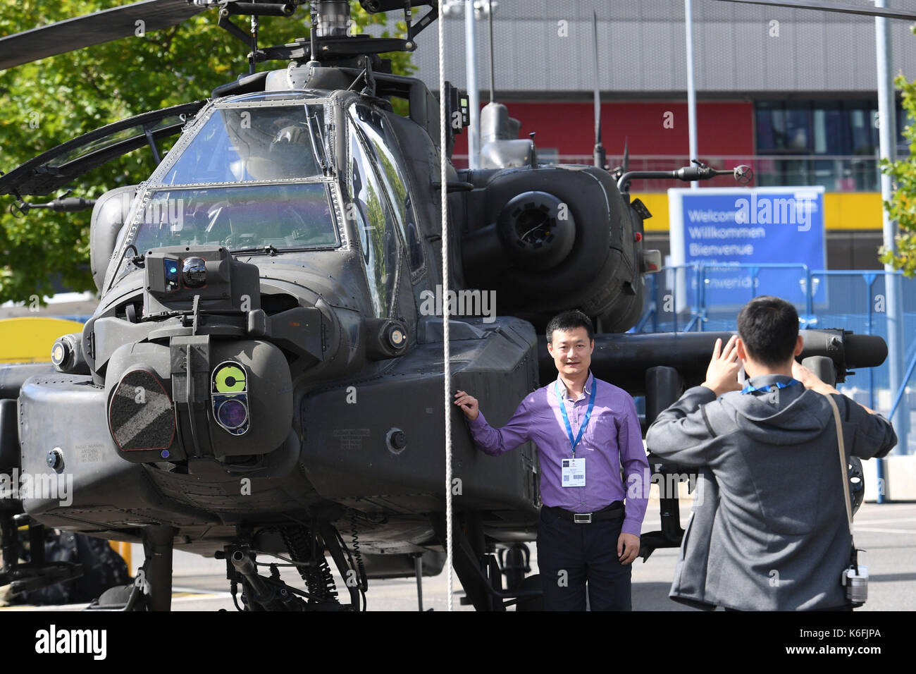 I visitatori di scattare una foto accanto a un Boeing AH-64 attacco Apache elicottero durante la difesa di sistemi e apparecchiature di armi a livello internazionale fiera presso il centro excel di Londra. Foto Stock