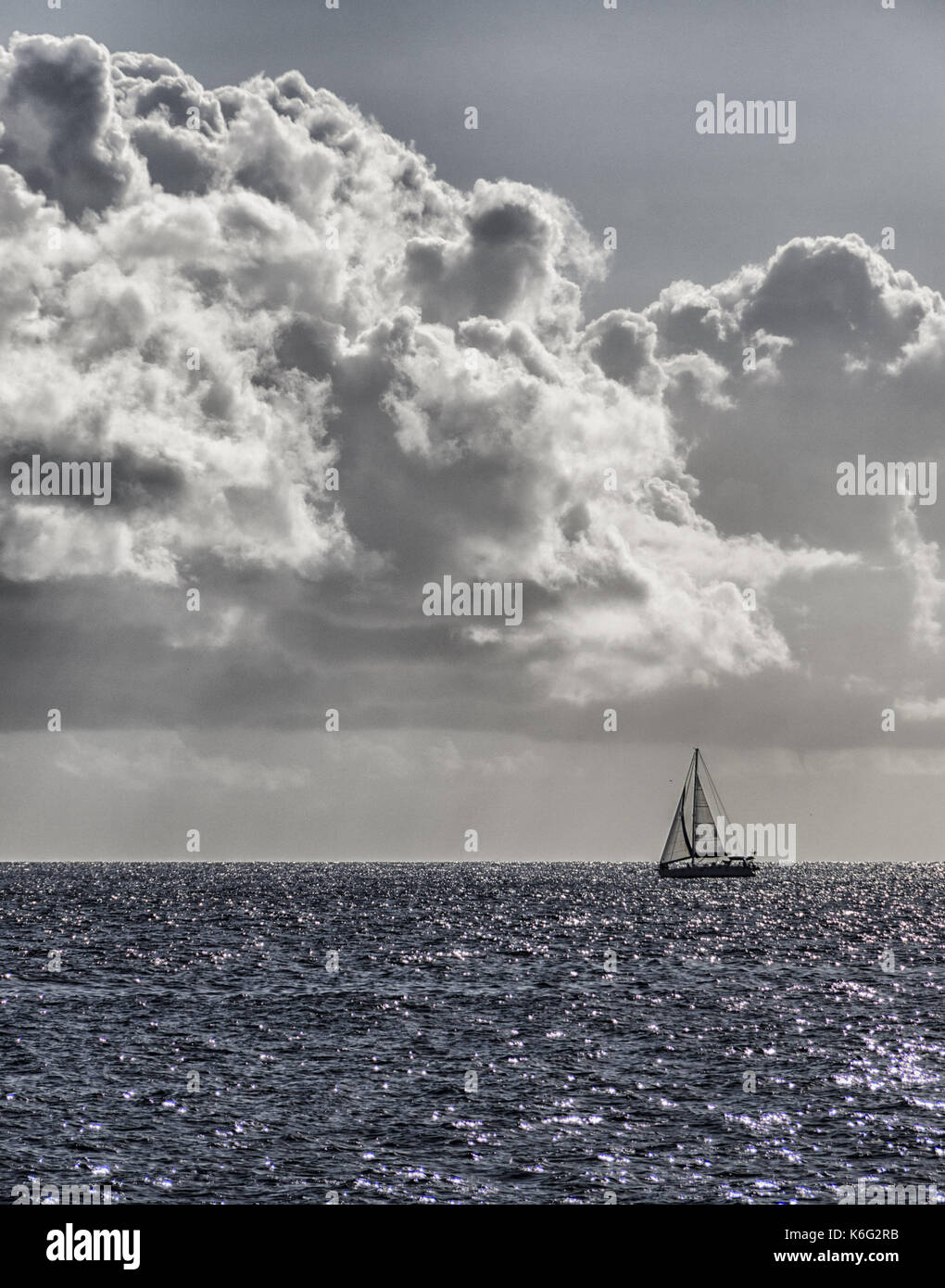 Fotografia in bianco e nero di uno yacht solitario all'orizzonte Foto Stock