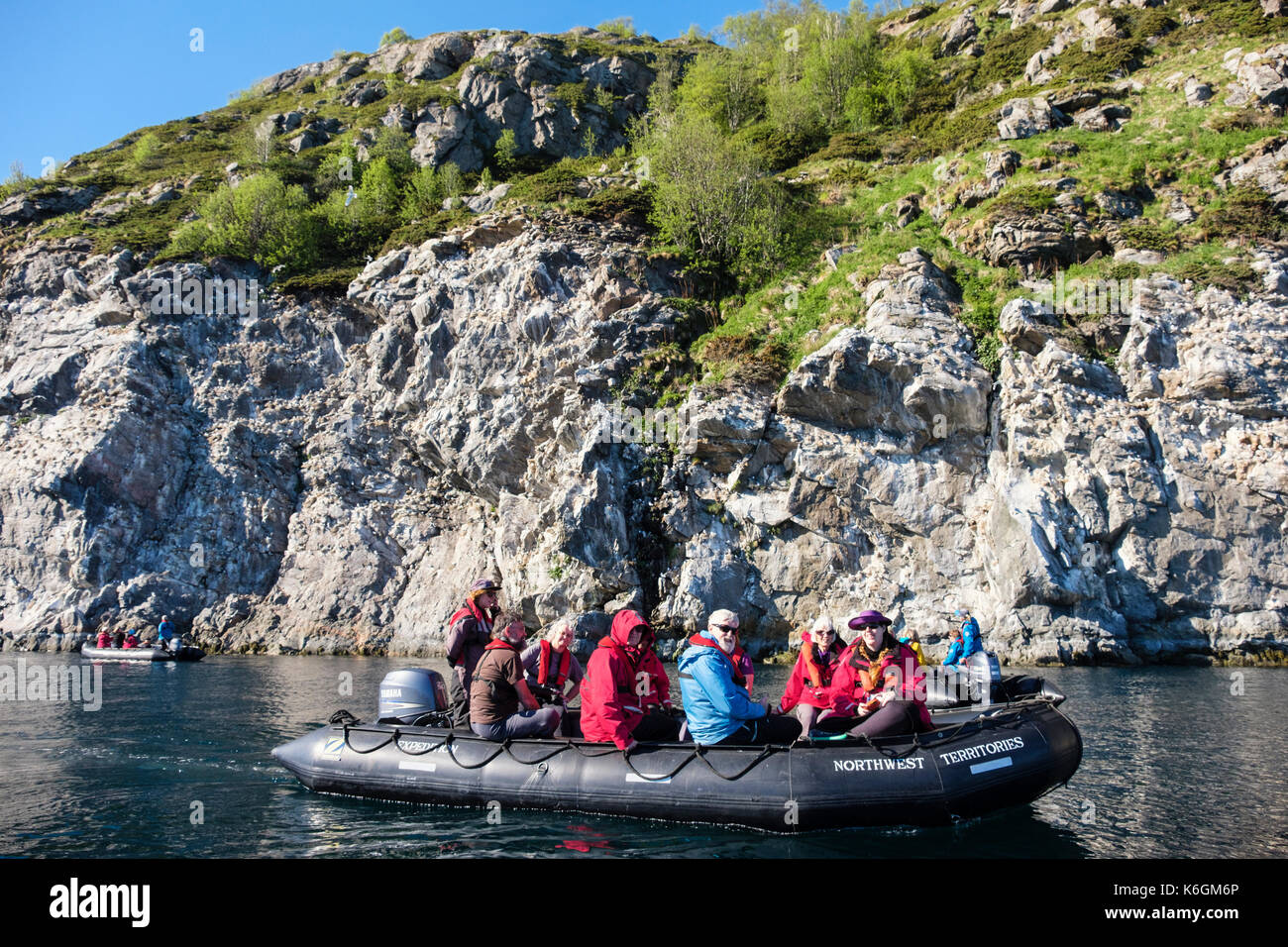 G avventure i passeggeri delle crociere in gommone Zodiac visitando la nidificazione nero-Kittiwakes zampe su scogliere sul mare in Sundsvollsundet Riserva Naturale, Norvegia Foto Stock