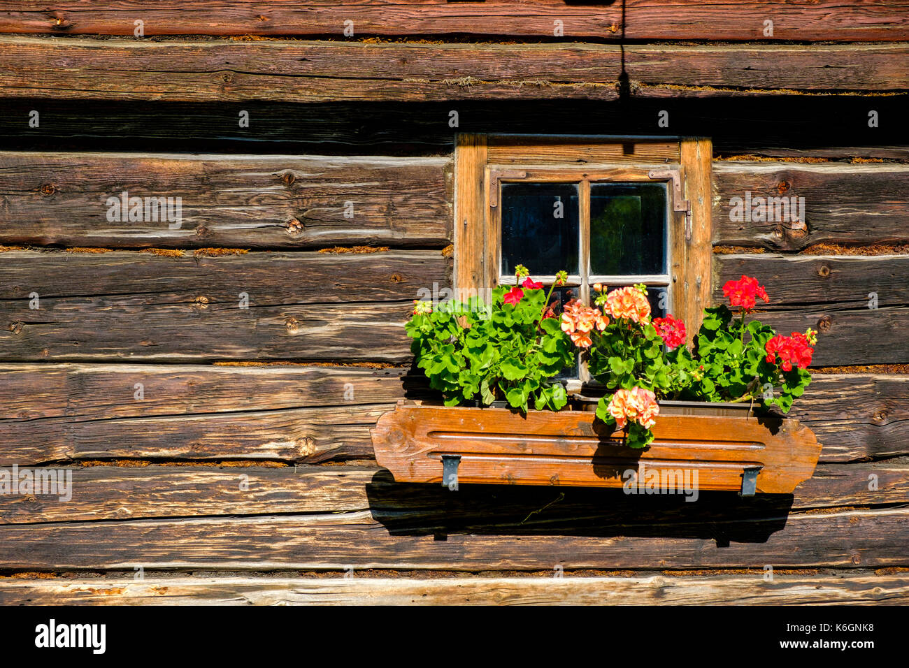 La piccola finestra di una vecchia casa colonica in legno e decorate con  fiori colorati Foto stock - Alamy