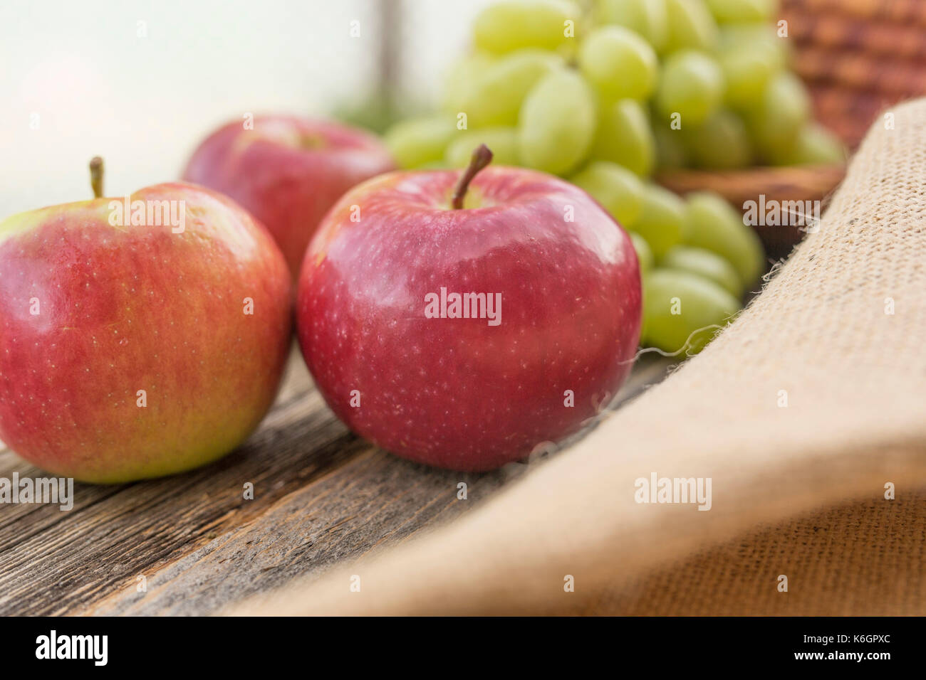 Primo piano di un tavolo d'annata con mele in primo piano e uvetta sullo sfondo. Decorazione di una vita semplice all'aperto. Foto Stock