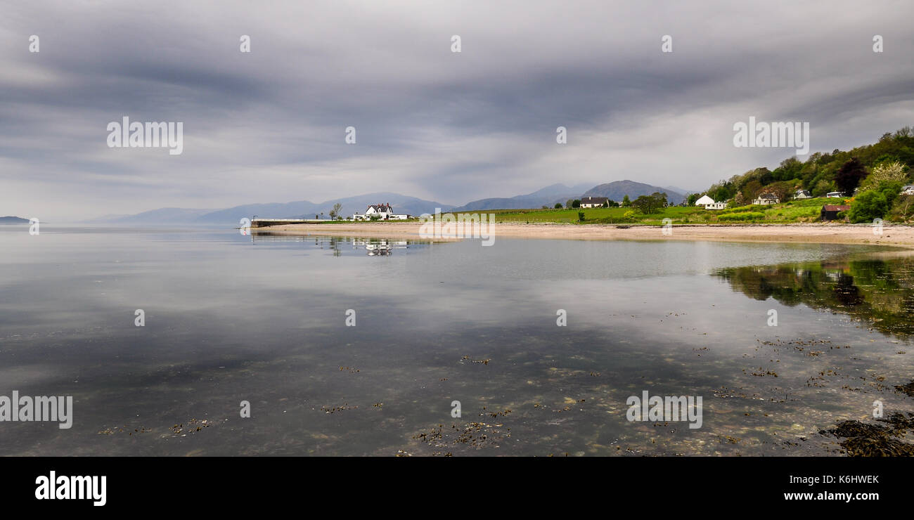 Una casa sorge su una piccola penisola, che si riflette nel mare calmo sulle rive di Loch linnhe nel west Highlands della Scozia. Foto Stock