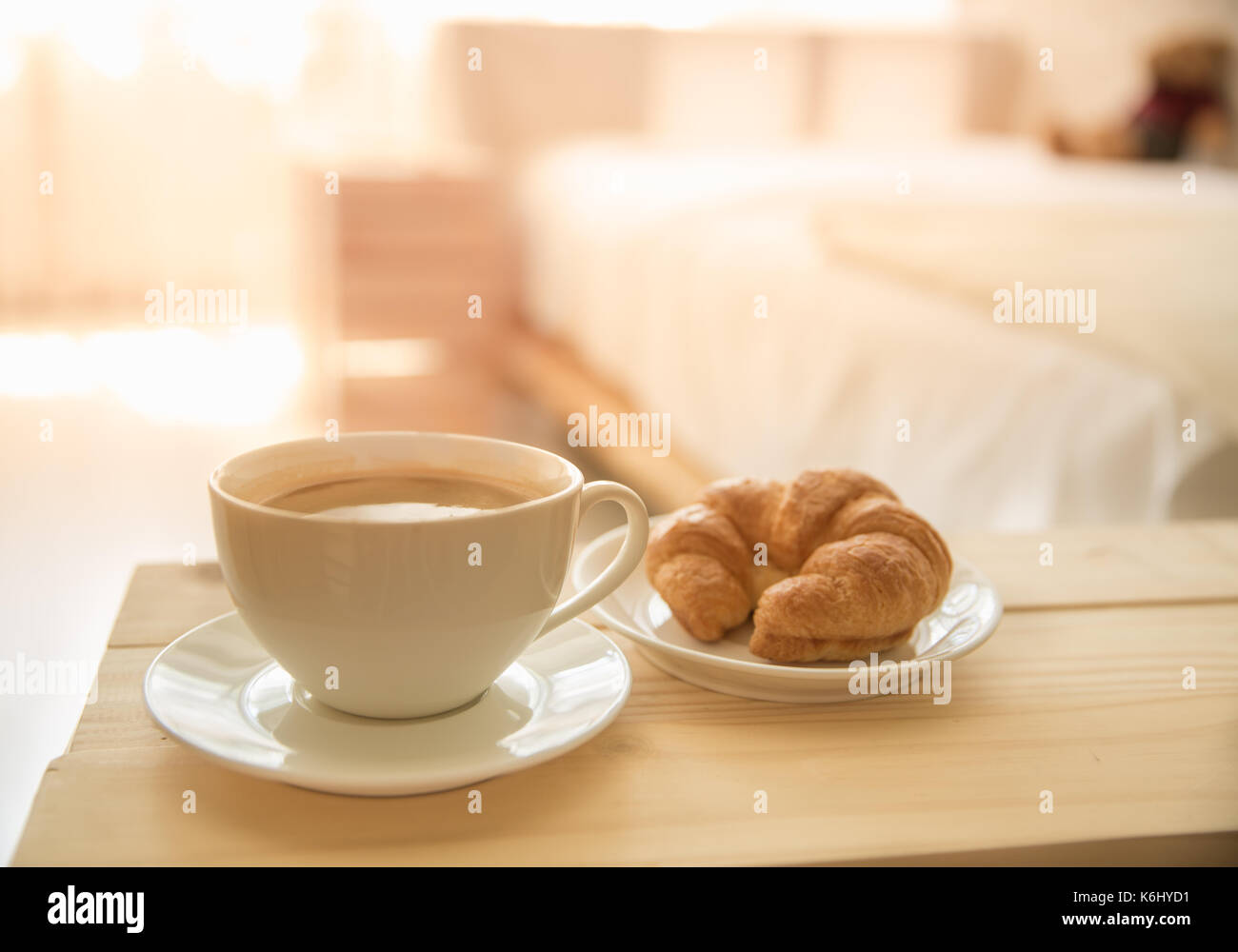 Caffè caldo e il cornetto al mattino con la camera da letto la sfocatura sullo sfondo Foto Stock