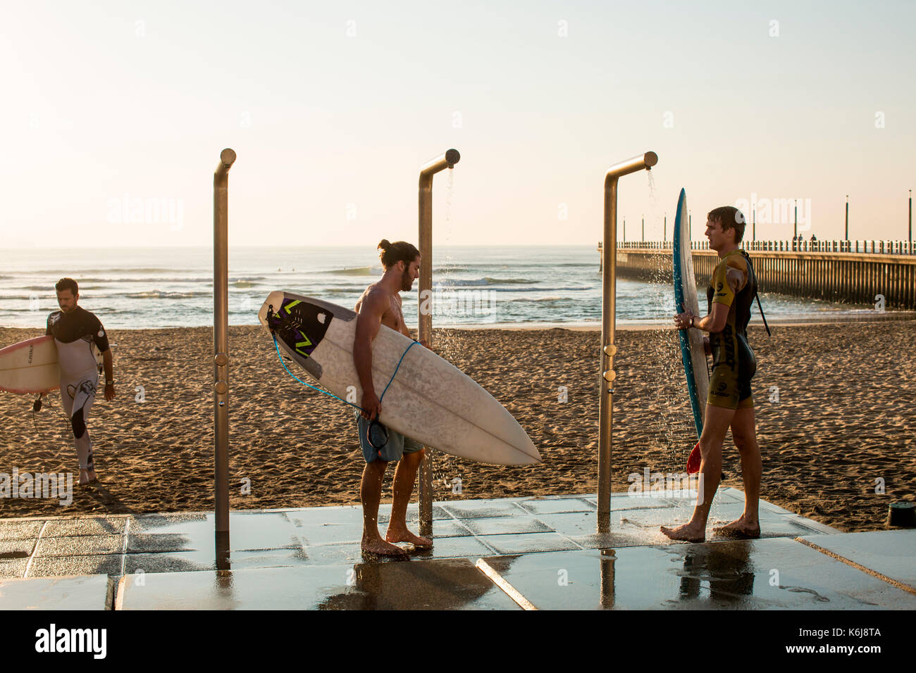 Lavaggio degli uomini verso il basso le tavole da surf vicino al promenade sul Golden Mile di Durban, Sud Africa Foto Stock