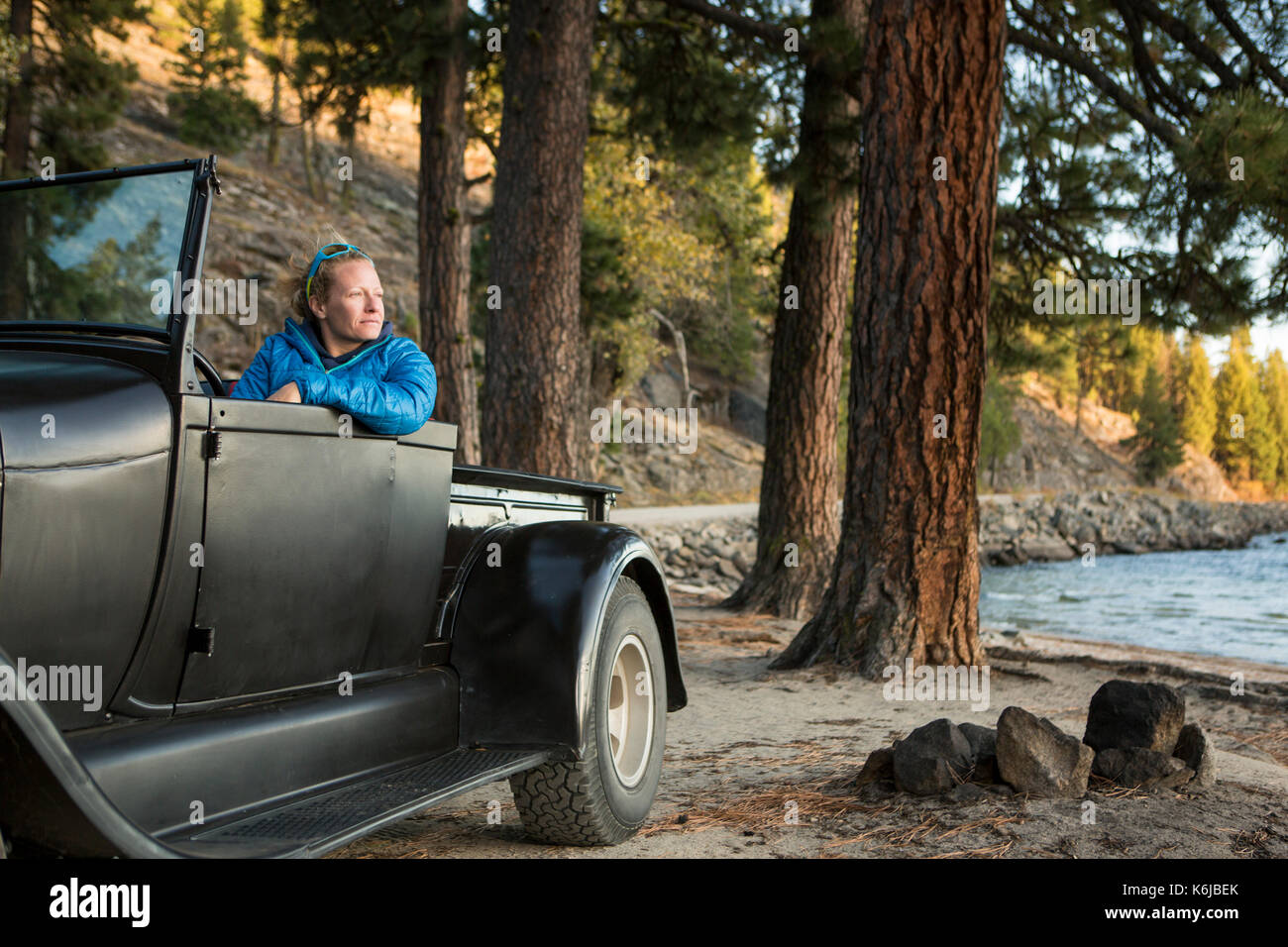 Donna seduta nel rinnovato carrello guardando il tramonto sul Lago Payette, McCall, Idaho, Stati Uniti d'America Foto Stock