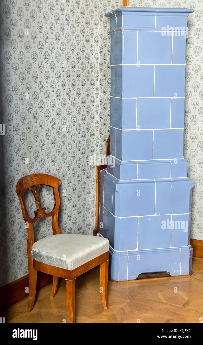 Storico di stufa in piastrelle in un angolo della sala con una decorazione a sedia imbottita. Foto Stock