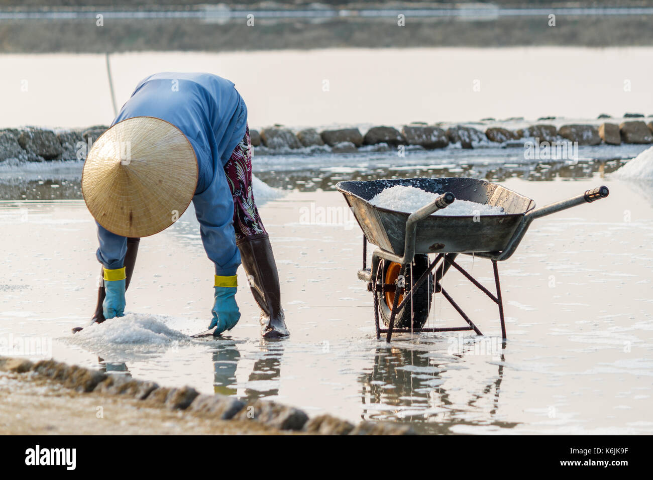 Una donna raccoglie il sale a hon khoi campi di sale in Nha Trang, Vietnam. Foto Stock