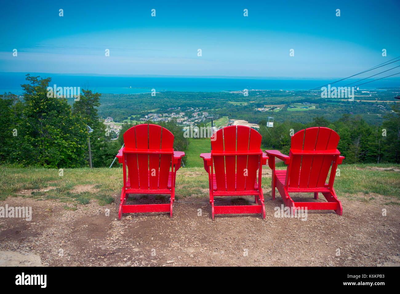 Vista di 3 rosso di muskoka sedie a Blue Mountain Resort e villaggio durante l'estate in Collingwood, Ontario Foto Stock