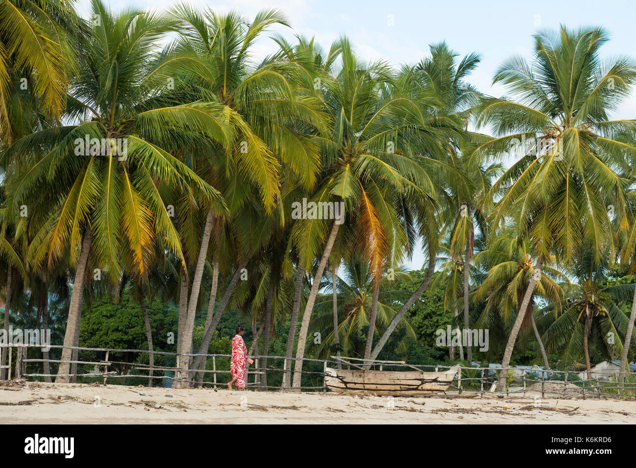 Donna che cammina sulle palme spiaggia, Nosy Be, Madagascar Foto Stock