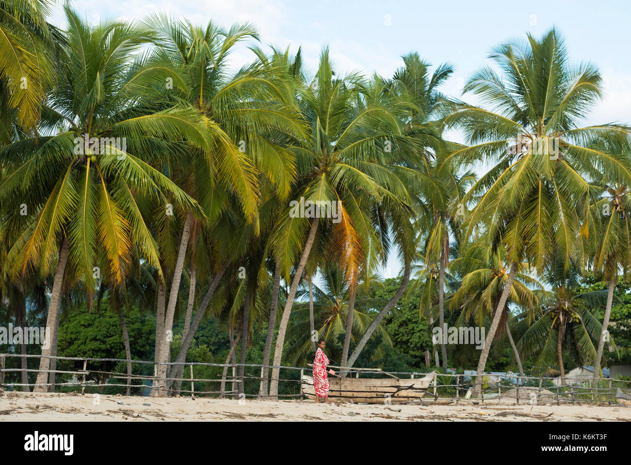 Donna che cammina sulle palme spiaggia, Nosy Be, Madagascar Foto Stock