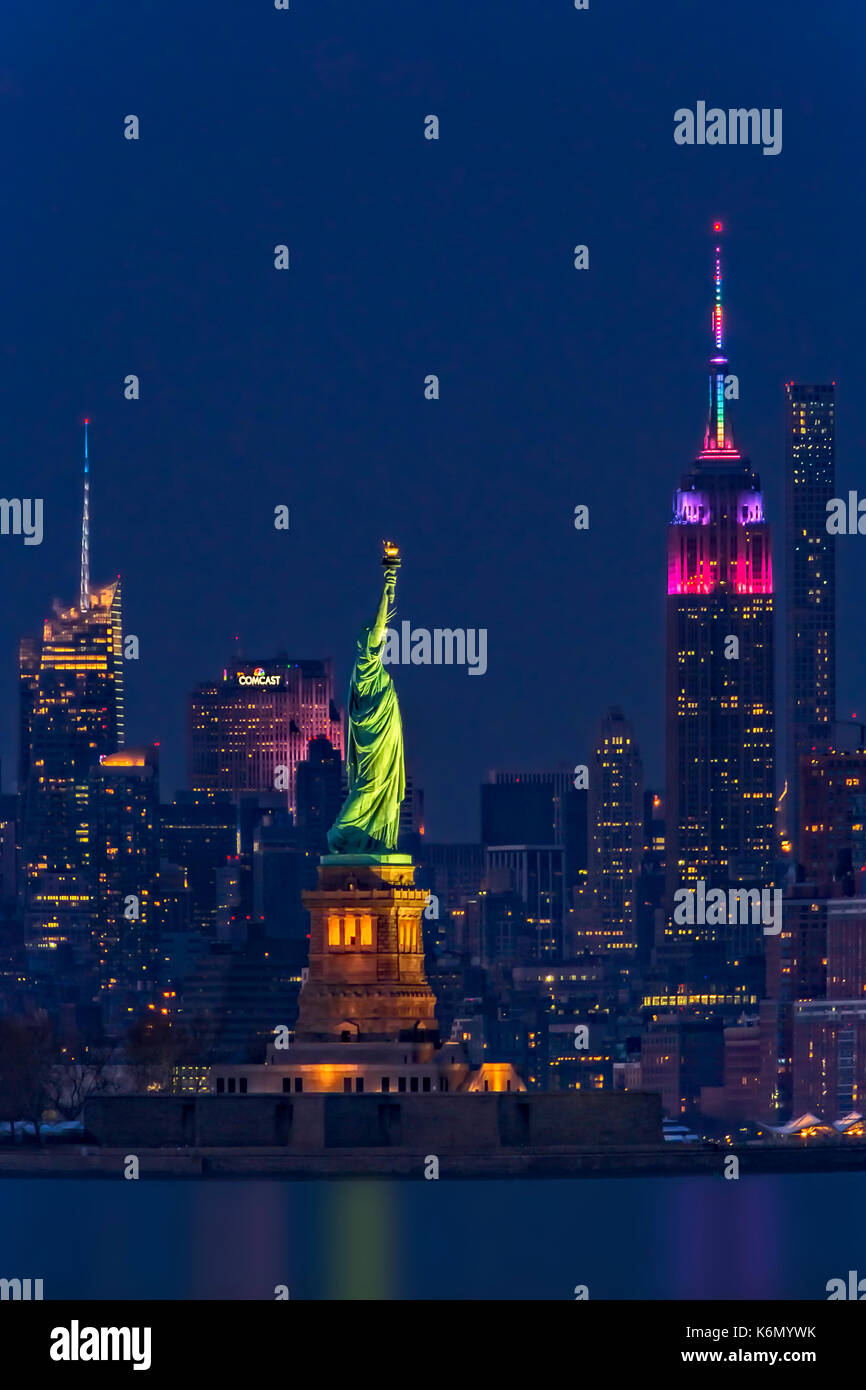 Empire State e la Statua della Libertà - Gli illuminati midtown skyline di Manhattan con l' Empire State Building (ESB) illuminato con i colori della rainb Foto Stock