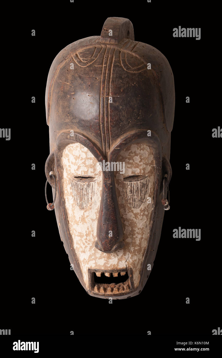 Un africano maschera cerimoniale nella forma di una figura femminile scolpita in legno isolato su nero. Foto Stock