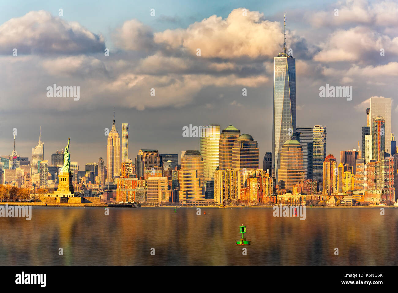 New York City icone II - Il sole che riscalda il midtown skyline di Manhattan con l' Empire State Building (ESB). Si vede anche la Statua della Libertà Foto Stock