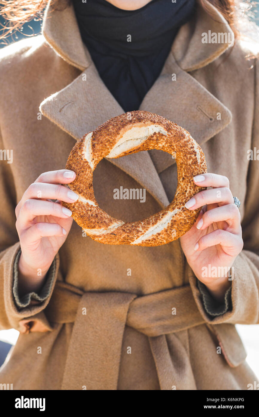 Bella donna contiene un tradizionale bagno turco simit in mani e vuole mangiare Foto Stock