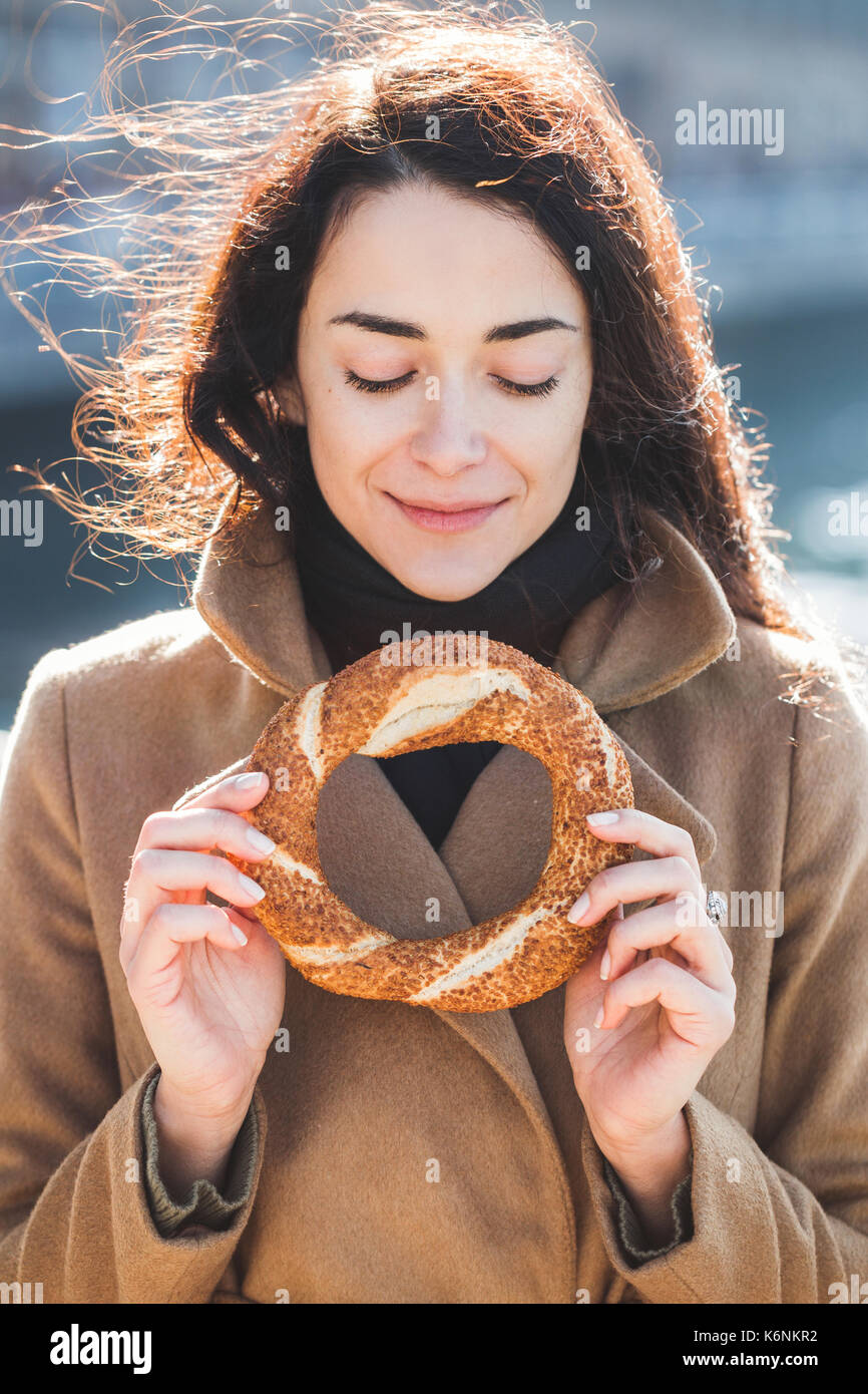 Bella donna contiene un tradizionale bagno turco simit in mani e vuole mangiare Foto Stock